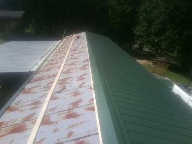 Old rusted panels beside newly installed green metal roofing — Wind Damage Roof Repair by Roofing Brothers in Preston Park