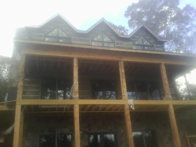 Dormers and porch framing on a large log home under construction — Roof Coating work by our crew in Preston Park