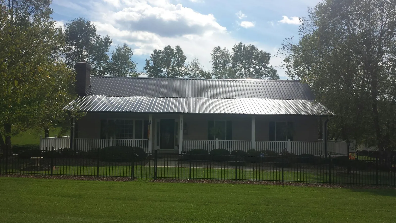 Gray metal roof on a brick ranch with a full width front porch — Gutter Guard Installation work by our crew in Preston Park