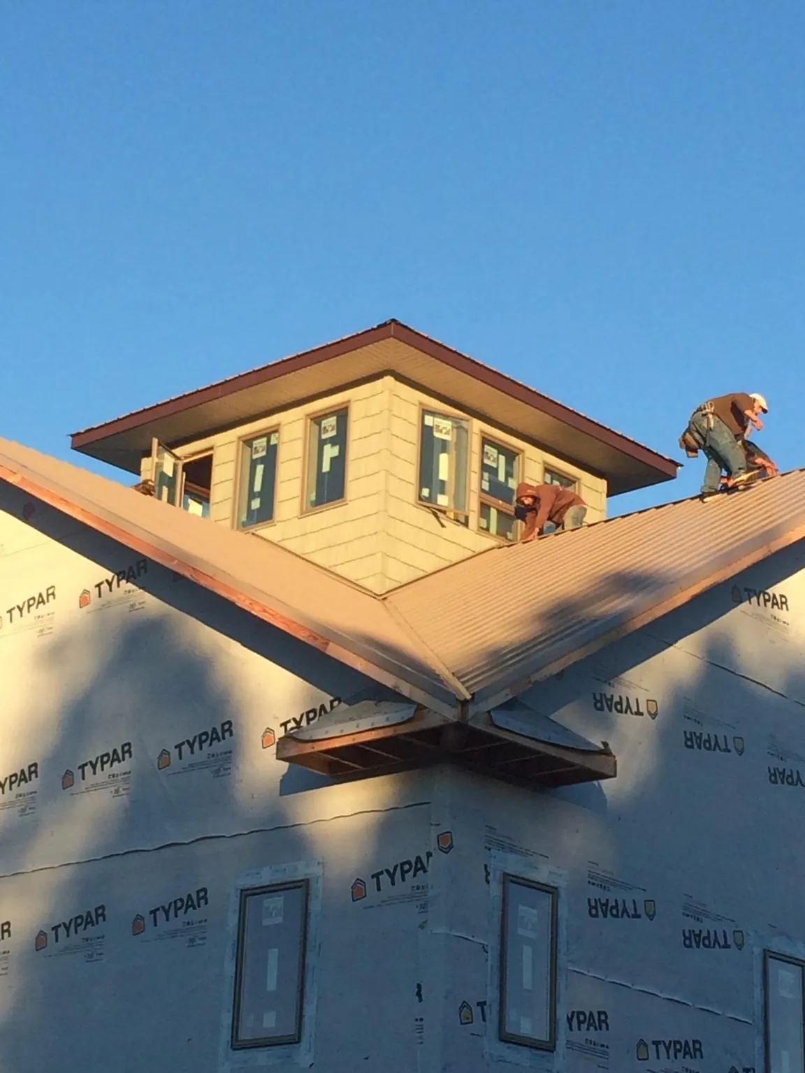 Roofers working around a rooftop cupola on a new metal roof at sunset — Roof Waterproofing in Preston Park by Roofing Brothers
